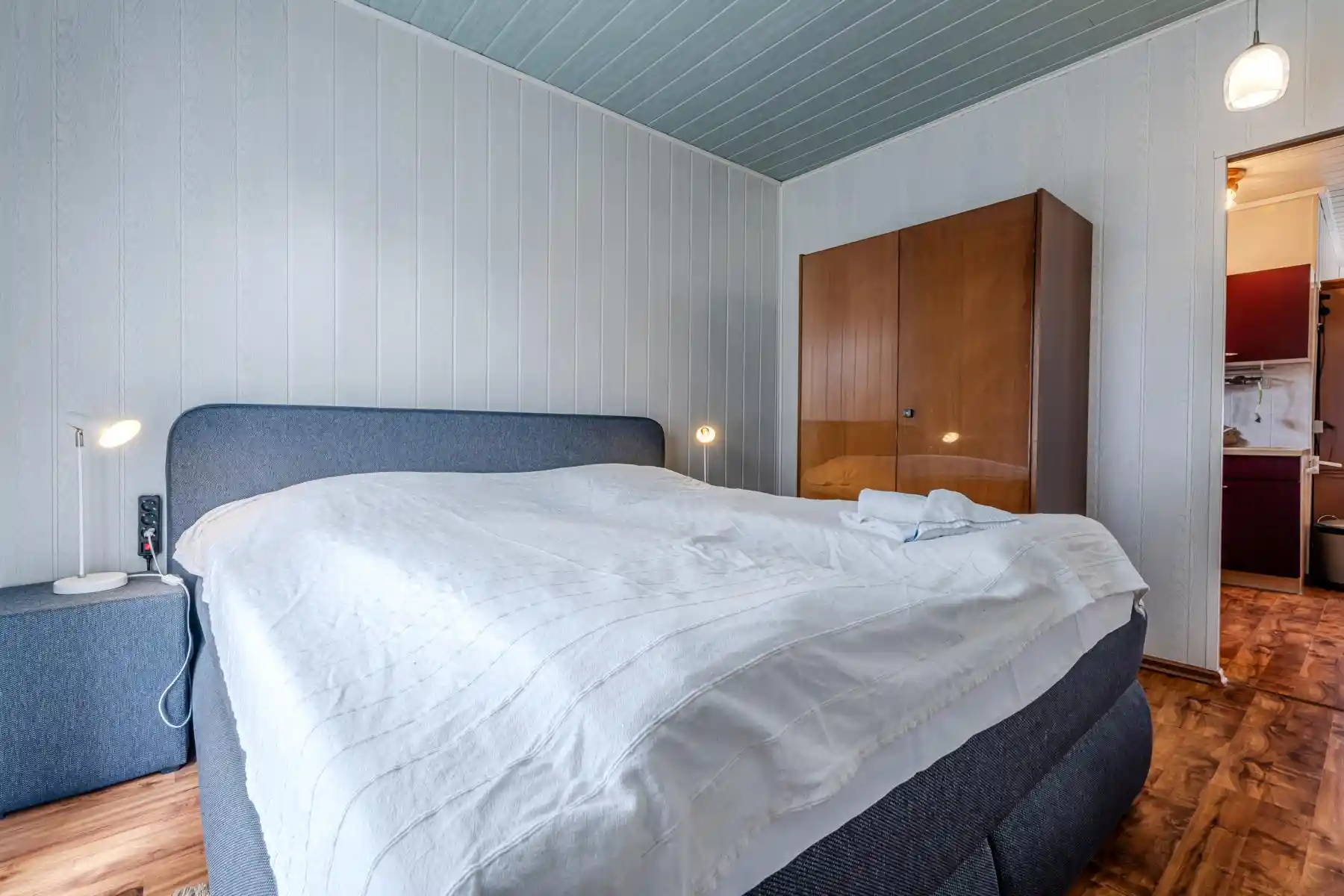 Auf diesem Bild sehen Sie das erste Schlafzimmer des Ferienhauses der Villa See-Eck im Seebad Ahlbeck auf der Insel Usedom von https://aufnachusedom.de. Es sind ein Boxspringbett für zwei Personen und ein Kleiderschrank zu sehen.