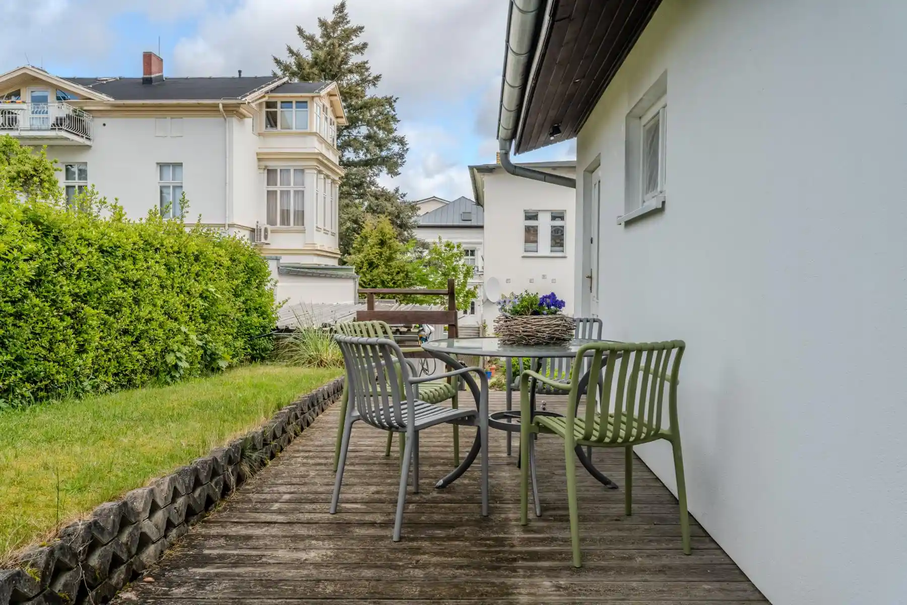 Auf diesem Bild sehen Sie die Terrasse mit einem Tisch und vier Gartenstühlen des Ferienhauses der Villa See-Eck im Seebad Ahlbeck auf der Insel Usedom von https://aufnachusedom.de aus einer anderen Perspektive. Es sind ein Boxspringbett für zwei Personen und ein Kleiderschrank zu sehen.