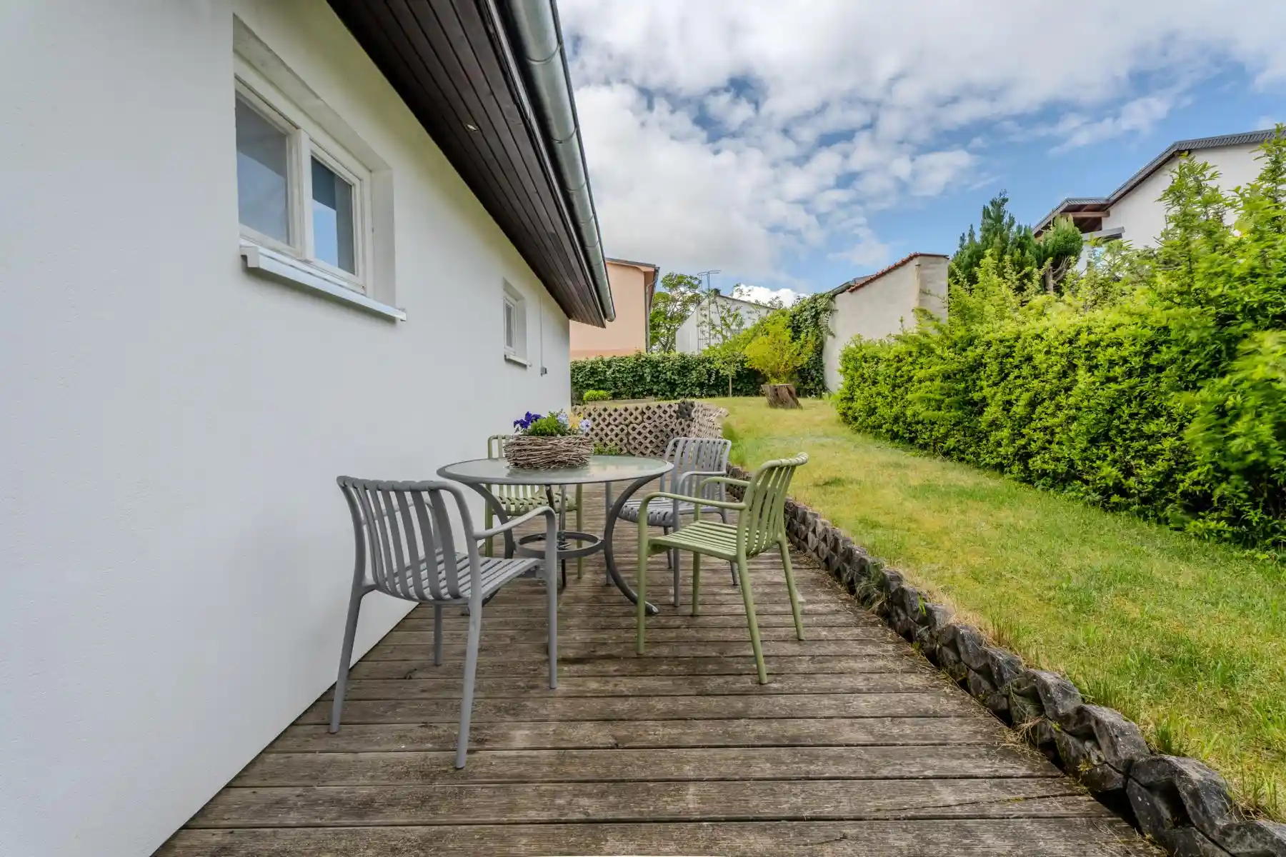 Auf diesem Bild sehen Sie die Terrasse mit einem Tisch und vier Gartenstühlen des Ferienhauses der Villa See-Eck im Seebad Ahlbeck auf der Insel Usedom von https://aufnachusedom.de. Es sind ein Boxspringbett für zwei Personen und ein Kleiderschrank zu sehen.