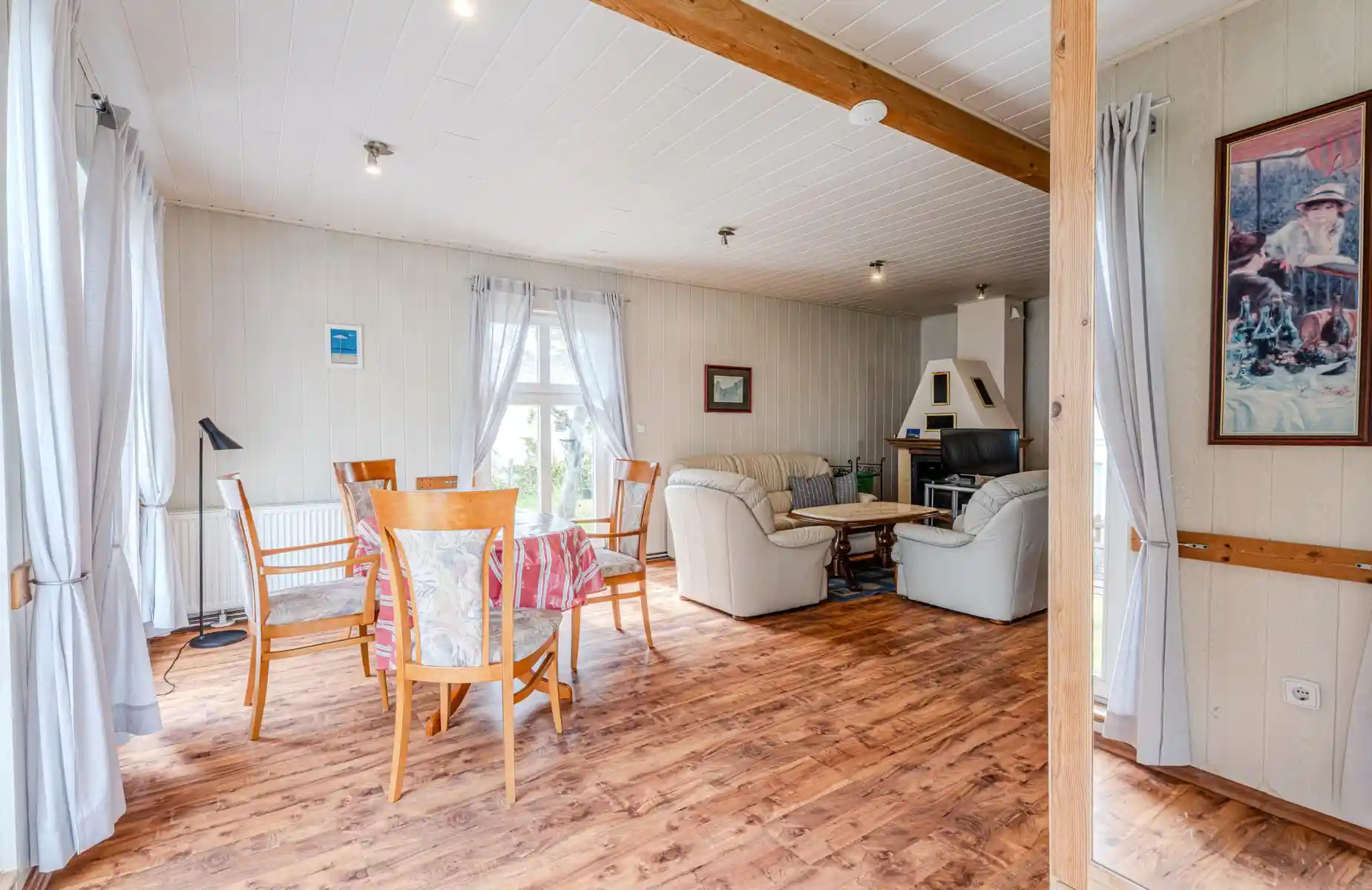 Auf diesem Bild sehen Sie das Wohnzimmer mit Esstisch, Couch-Garnitur, Kamin, Fernseher des Ferienhauses der Villa See-Eck im Seebad Ahlbeck auf der Insel Usedom von https://aufnachusedom.de - Bild 2.