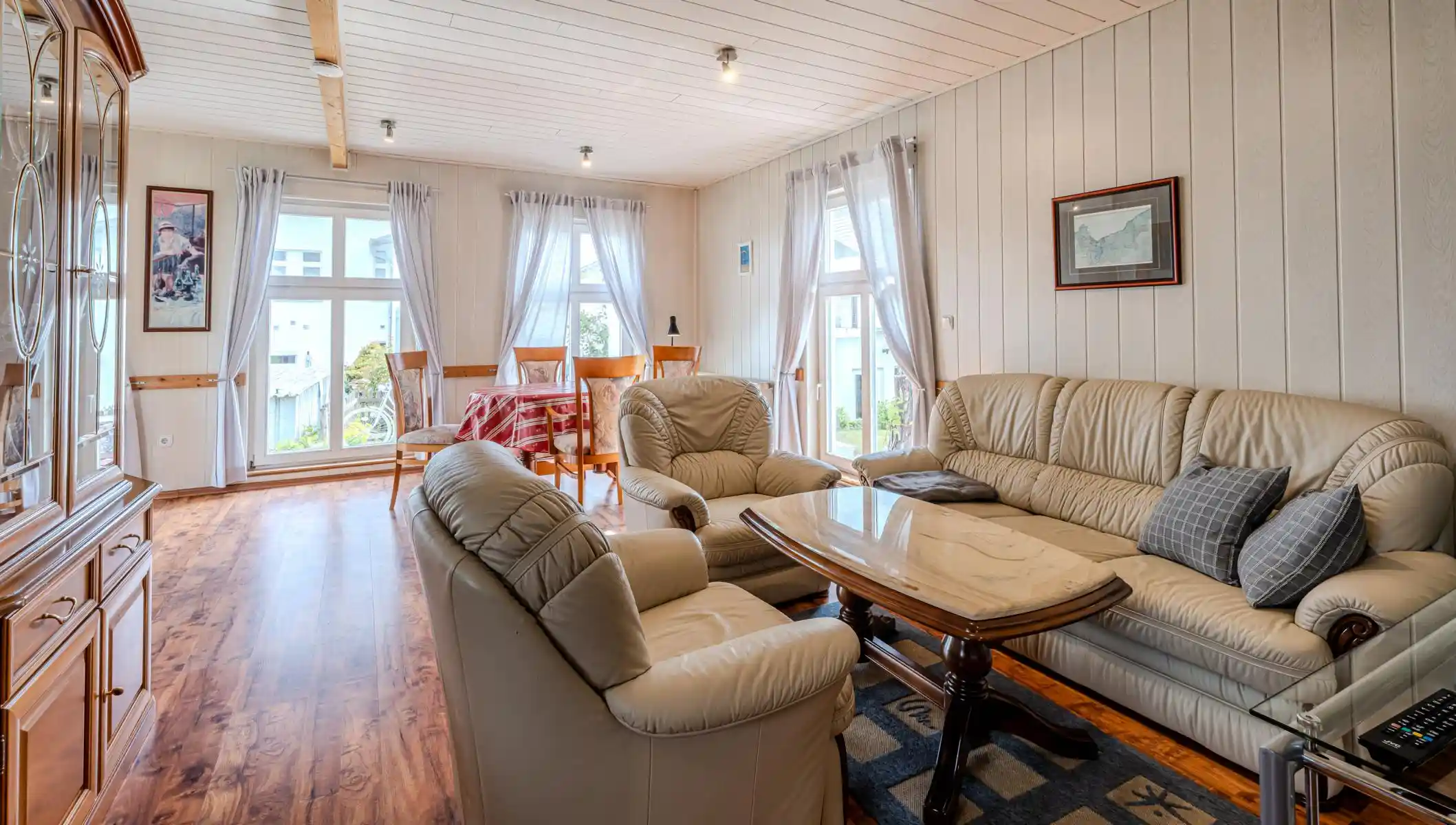 Auf diesem Bild sehen Sie das Wohnzimmer mit Esstisch, Couch-Garnitur und Anbauwand des Ferienhauses der Villa See-Eck im Seebad Ahlbeck auf der Insel Usedom von https://aufnachusedom.de.