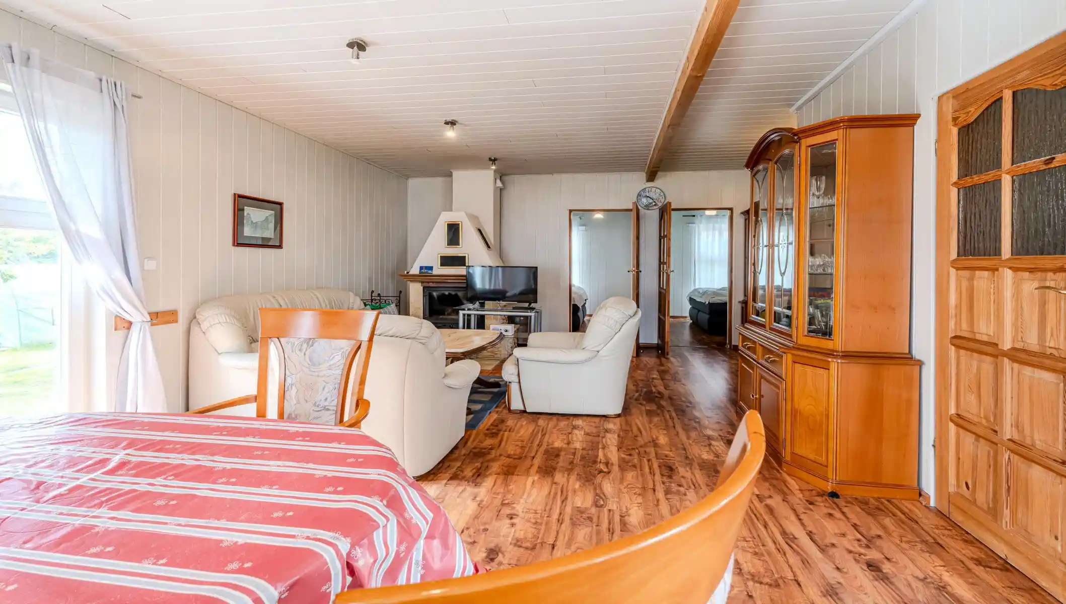 Auf diesem Bild sehen Sie das Wohnzimmer mit Esstisch, Couch-Garnitur, Kamin, Fernseher und Anbauwand des Ferienhauses der Villa See-Eck im Seebad Ahlbeck auf der Insel Usedom von https://aufnachusedom.de.