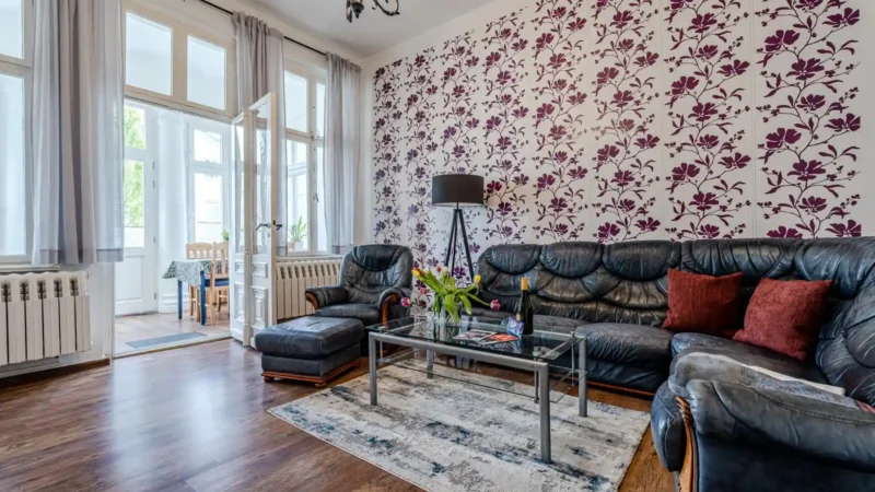 Auf diesem Bild sehen Sie das Wohnzimmer mit Couch-Garnitur und Blick auf die geschlossene Veranda mit großer Fensterfront in der Ferienwohnung 75 Quadratmeter im Erdgeschoss des Ferienhauses der Villa See-Eck im Seebad Ahlbeck auf der Insel Usedom von https://aufnachusedom.de.